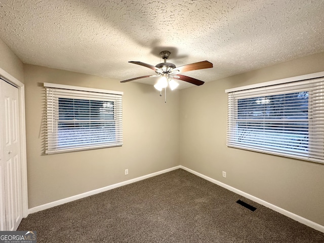 unfurnished bedroom featuring ceiling fan, a closet, a textured ceiling, and carpet