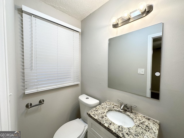 bathroom with vanity, toilet, and a textured ceiling