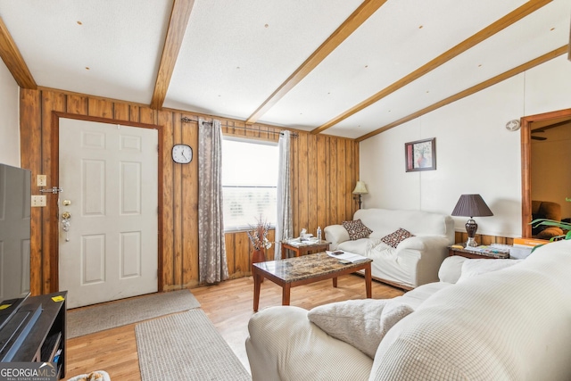 living room featuring vaulted ceiling with beams, wooden walls, and light hardwood / wood-style floors