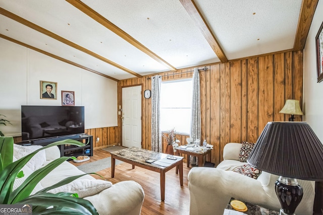 living room with hardwood / wood-style flooring, wooden walls, lofted ceiling with beams, and a textured ceiling