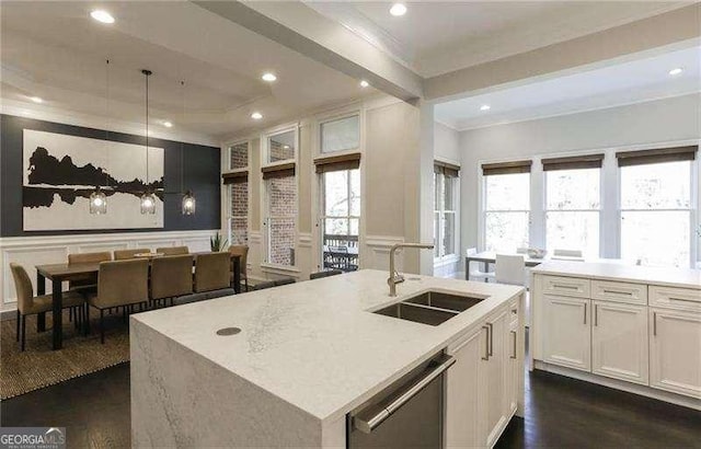 kitchen with sink, dishwasher, a kitchen island with sink, hanging light fixtures, and white cabinets