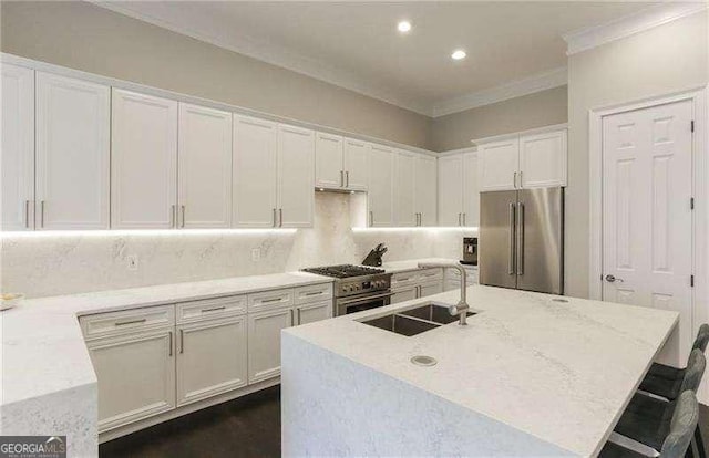 kitchen featuring sink, white cabinetry, premium appliances, a kitchen breakfast bar, and an island with sink