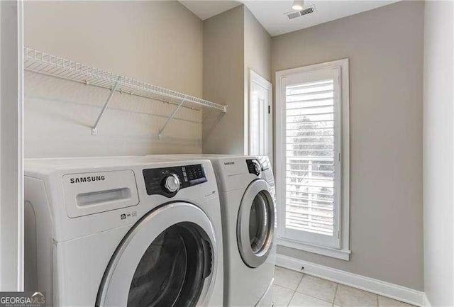 washroom with light tile patterned flooring, plenty of natural light, and washing machine and dryer