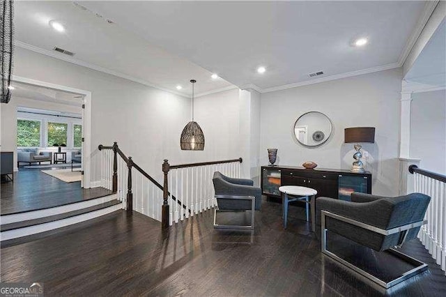 living area featuring crown molding, dark hardwood / wood-style floors, and ornate columns