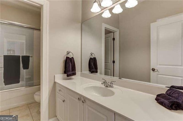 full bathroom with tile patterned flooring, bath / shower combo with glass door, vanity, and toilet