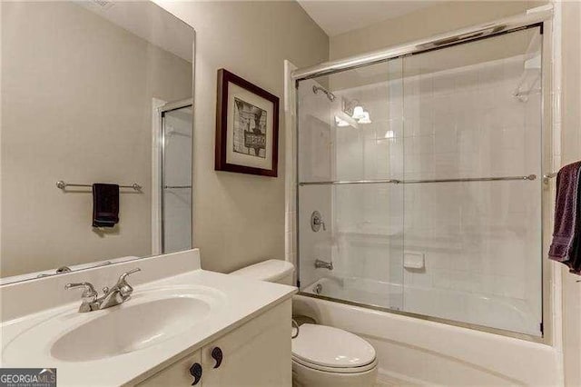 full bathroom with sink, bath / shower combo with glass door, and toilet