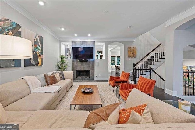 living room featuring hardwood / wood-style flooring, ornamental molding, and a tile fireplace