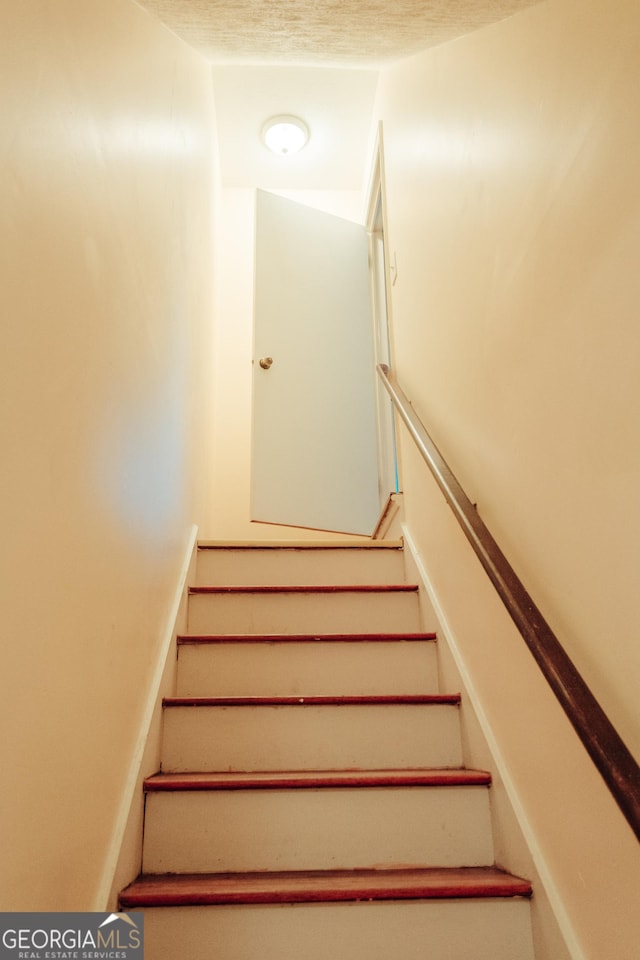 staircase featuring a textured ceiling