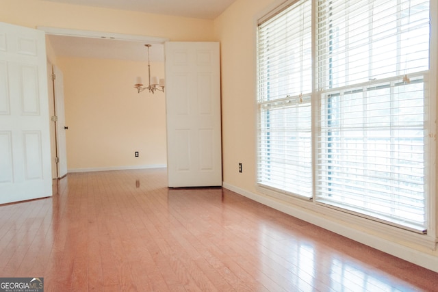 empty room with light wood-type flooring and an inviting chandelier