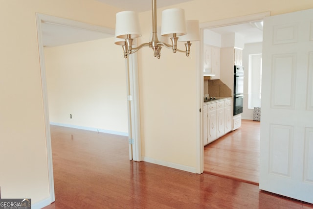 hallway with hardwood / wood-style floors and a chandelier