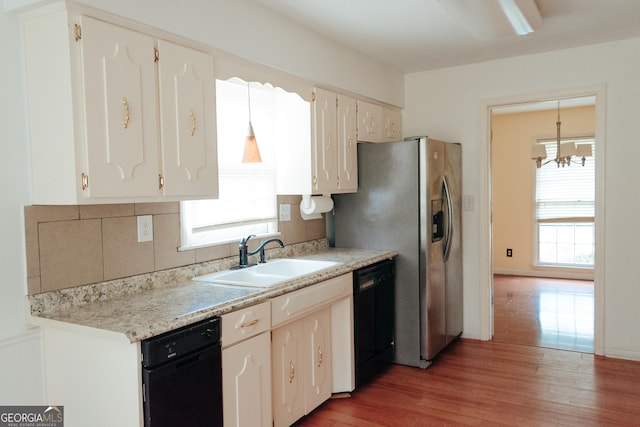 kitchen with hanging light fixtures, hardwood / wood-style flooring, black dishwasher, and sink