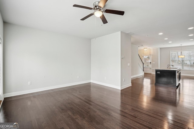 unfurnished living room with dark wood-type flooring, ceiling fan, and sink