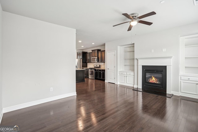 unfurnished living room featuring dark wood-type flooring, ceiling fan, and built in shelves