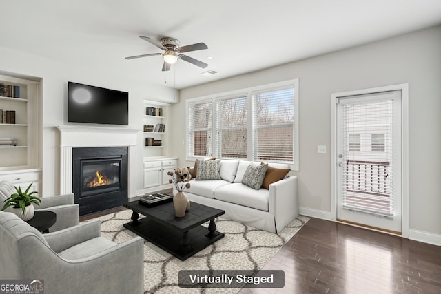 living room featuring a high end fireplace, built in features, dark hardwood / wood-style floors, and ceiling fan