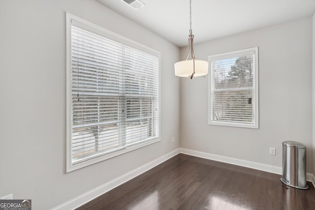 unfurnished dining area with dark wood-type flooring