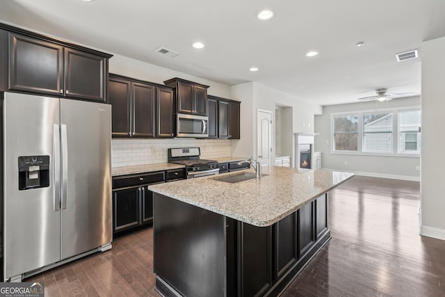 kitchen featuring sink, appliances with stainless steel finishes, dark hardwood / wood-style flooring, an island with sink, and decorative backsplash