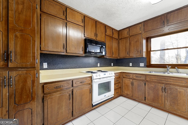 kitchen featuring sink, light tile patterned floors, a textured ceiling, and white range with electric stovetop