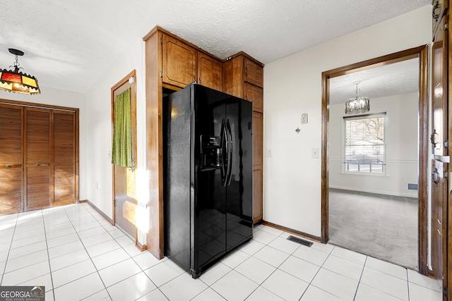 kitchen featuring pendant lighting, black fridge with ice dispenser, a textured ceiling, and light tile patterned floors