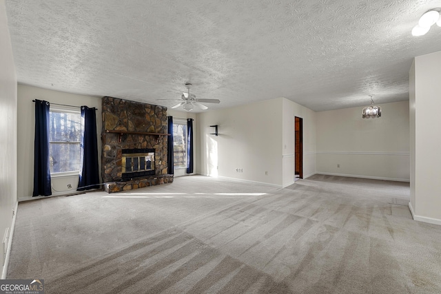 unfurnished living room featuring light carpet, a stone fireplace, ceiling fan with notable chandelier, and a textured ceiling