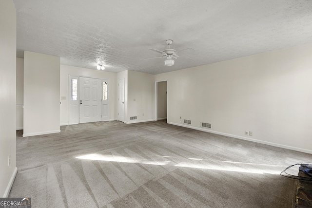 interior space with ceiling fan, light colored carpet, and a textured ceiling