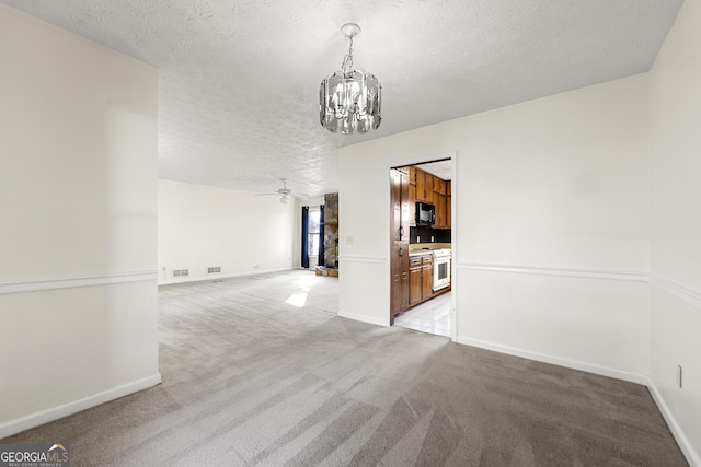 unfurnished room featuring ceiling fan with notable chandelier, light colored carpet, and a textured ceiling