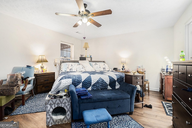 bedroom with a ceiling fan, baseboards, visible vents, and wood finished floors