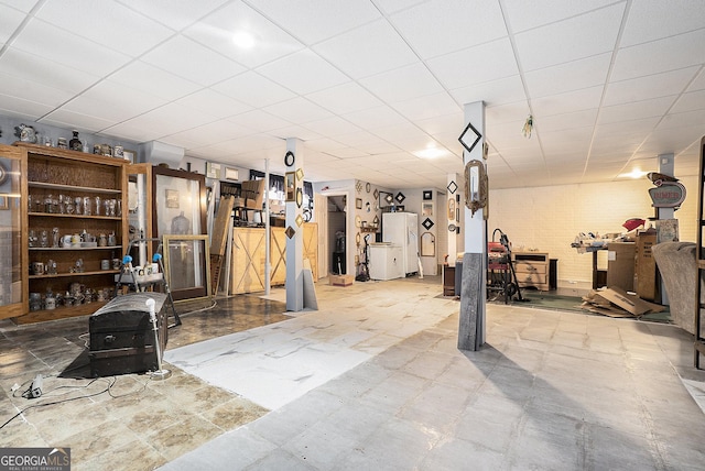 finished basement featuring freestanding refrigerator and a paneled ceiling