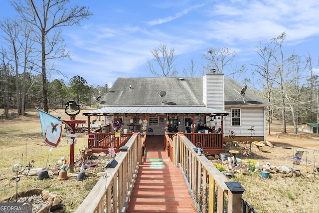 rear view of property with a shingled roof and a chimney