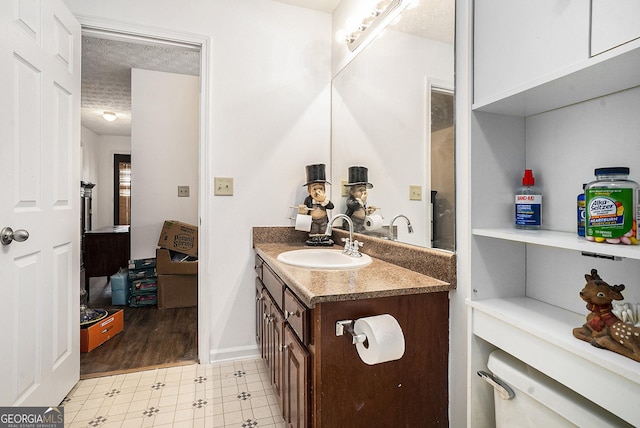 bathroom featuring tile patterned floors, baseboards, a textured ceiling, and vanity