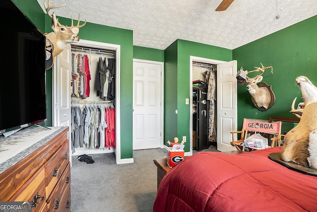 bedroom with baseboards, a ceiling fan, carpet, a textured ceiling, and two closets