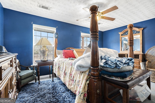 carpeted bedroom with a textured ceiling, visible vents, and a ceiling fan