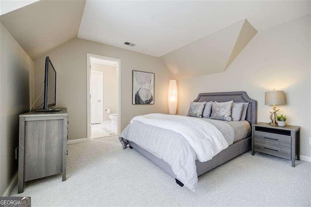 carpeted bedroom featuring ensuite bathroom and lofted ceiling