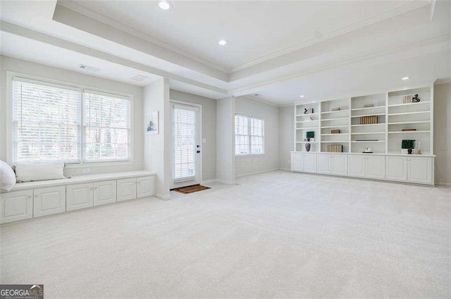 unfurnished living room with ornamental molding, light colored carpet, and a tray ceiling