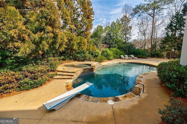 view of swimming pool featuring a patio area, a diving board, and an in ground hot tub