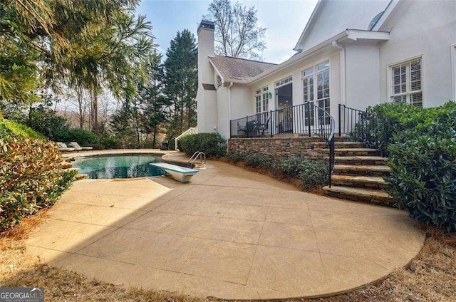 view of swimming pool featuring a diving board and a patio area