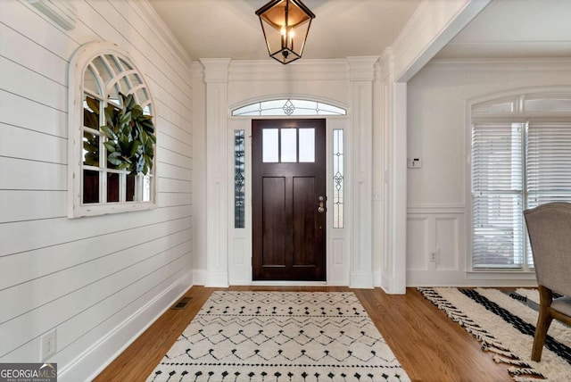 entrance foyer with ornamental molding and hardwood / wood-style floors