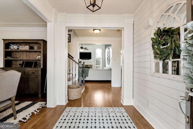 foyer featuring hardwood / wood-style flooring, ceiling fan, ornamental molding, and wood walls