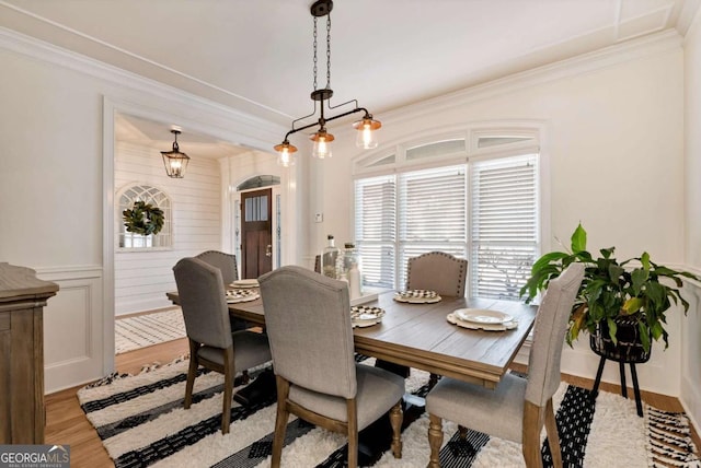 dining space with ornamental molding and light hardwood / wood-style floors