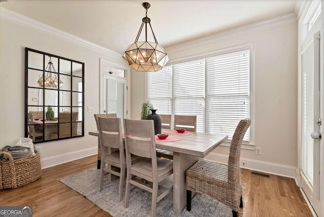 dining room with hardwood / wood-style floors, a notable chandelier, and ornamental molding