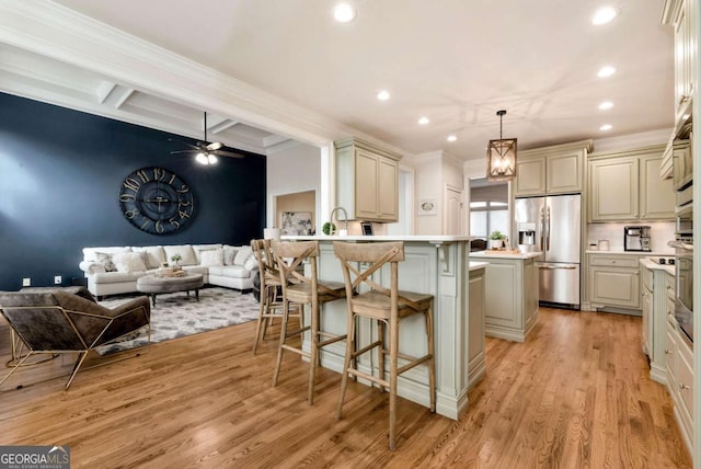 kitchen featuring a breakfast bar, a center island, stainless steel refrigerator with ice dispenser, cream cabinets, and decorative light fixtures