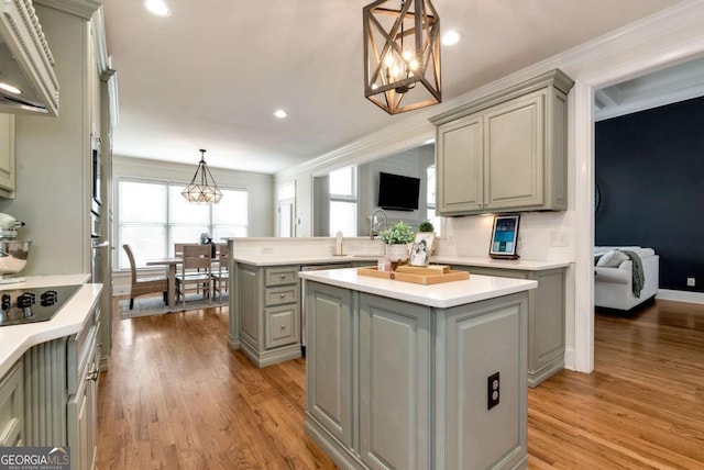 kitchen featuring gray cabinets, a kitchen island, decorative light fixtures, black electric stovetop, and light wood-type flooring