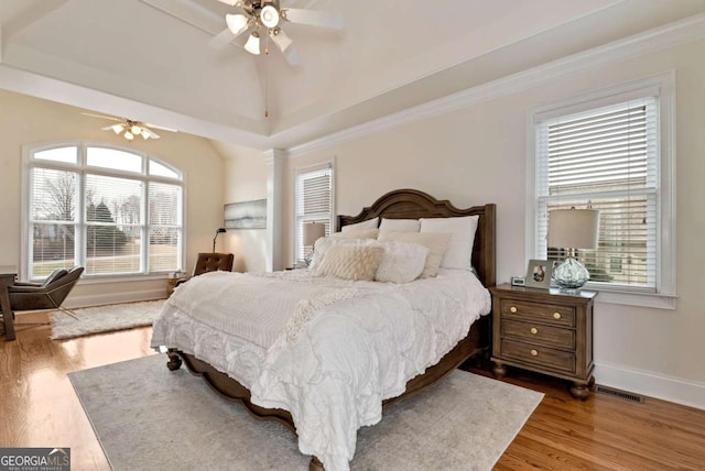 bedroom with lofted ceiling, wood-type flooring, ornamental molding, and ceiling fan