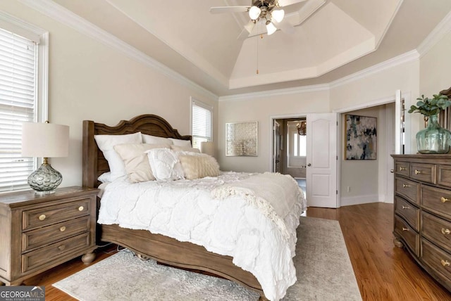 bedroom with lofted ceiling, dark wood-type flooring, ceiling fan, a tray ceiling, and ornamental molding