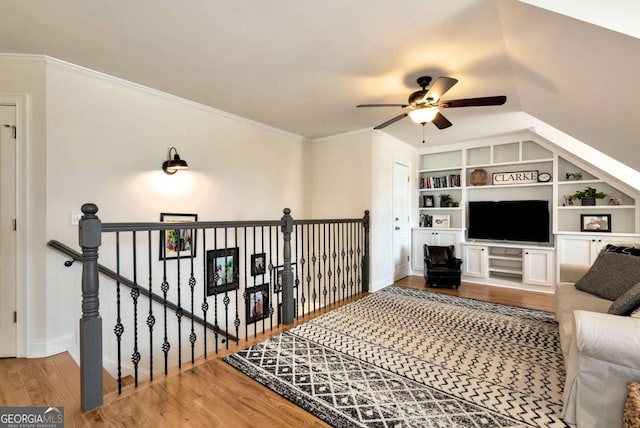 living room featuring crown molding, ceiling fan, hardwood / wood-style flooring, and built in shelves