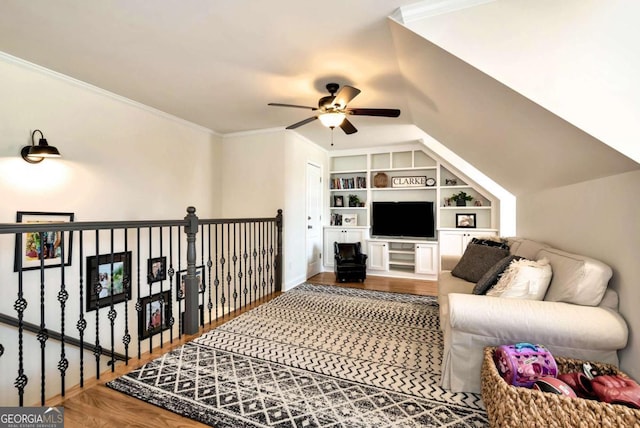 living room featuring built in shelves, ornamental molding, wood-type flooring, and ceiling fan