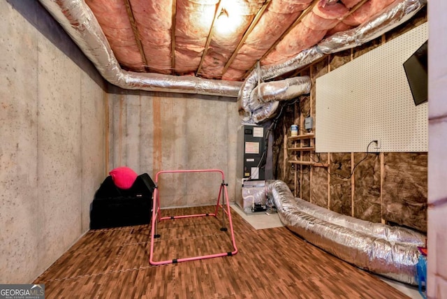 basement featuring heating unit and hardwood / wood-style flooring