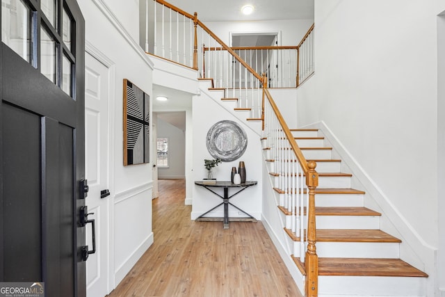 foyer entrance with a high ceiling and light hardwood / wood-style flooring