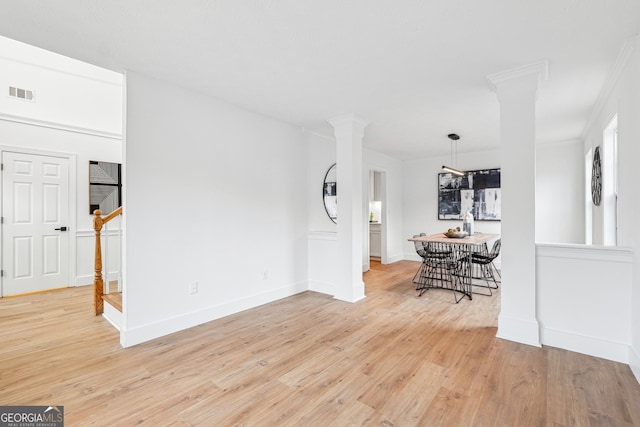 interior space featuring crown molding, light hardwood / wood-style floors, and ornate columns