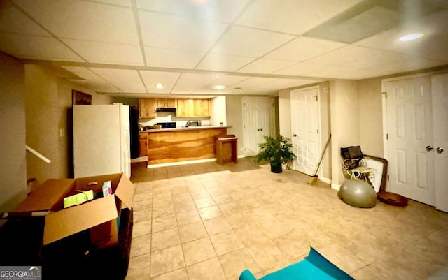 kitchen with white fridge, light brown cabinets, and a drop ceiling