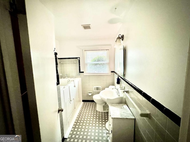 bathroom featuring vanity, toilet, and tile walls